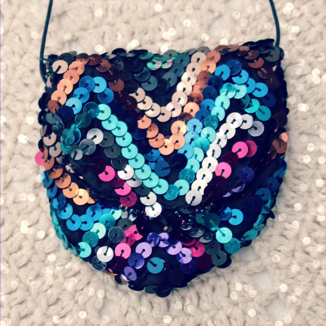 a multi - color sequinned purse sitting on top of a knitted cloth