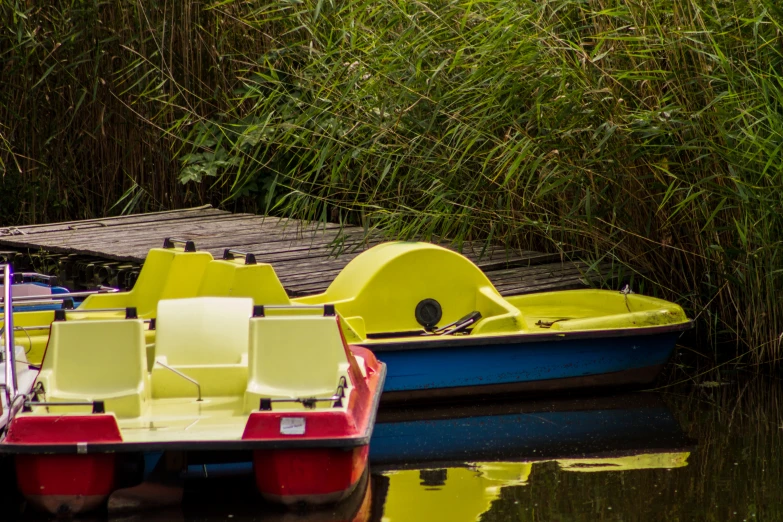 two different colored boats with seats parked by a dock