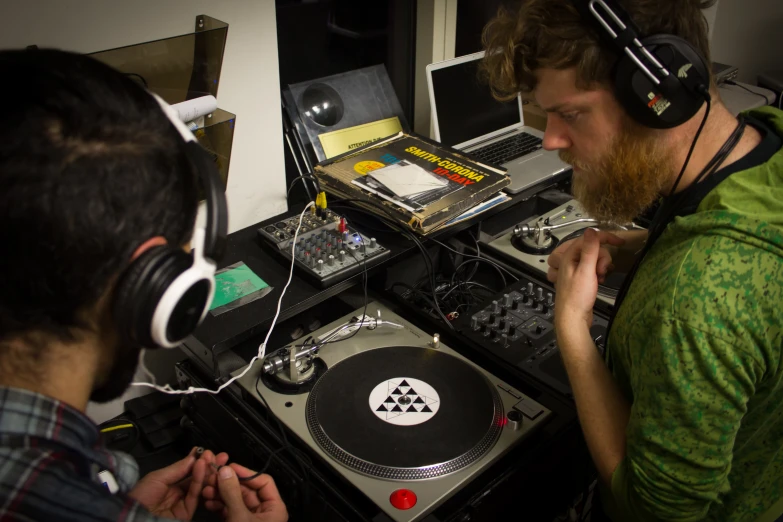 a man wearing headphones playing dj records with another person