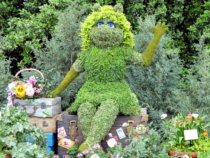 a fake plant character sitting in a garden filled with flowers