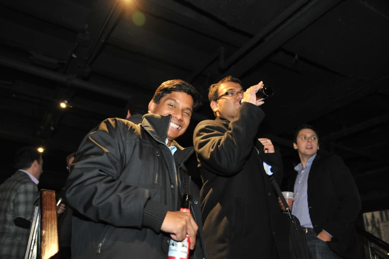 two men at an event hold beer and toast