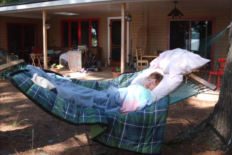 the little boy is sleeping on his own hammock