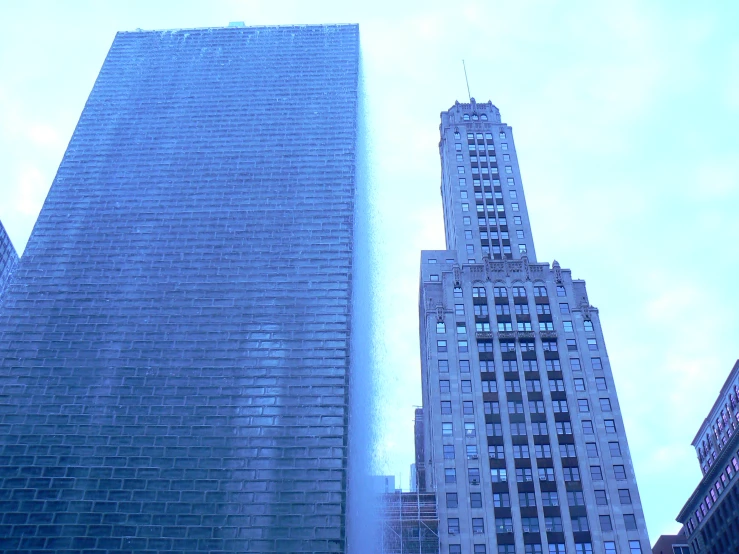 two tall buildings against a blue sky with few clouds