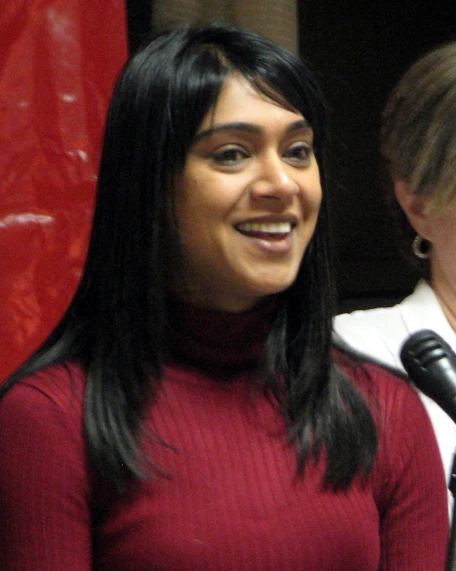 a woman standing by a microphone smiling
