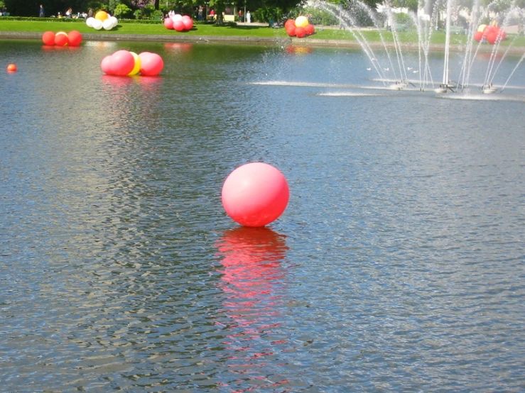 a pond with colorful floating balls and sprays