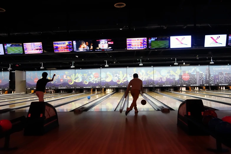 two people play a bowling game on a large screen