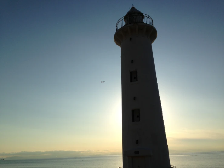 the sun shines through the clouds near a lighthouse