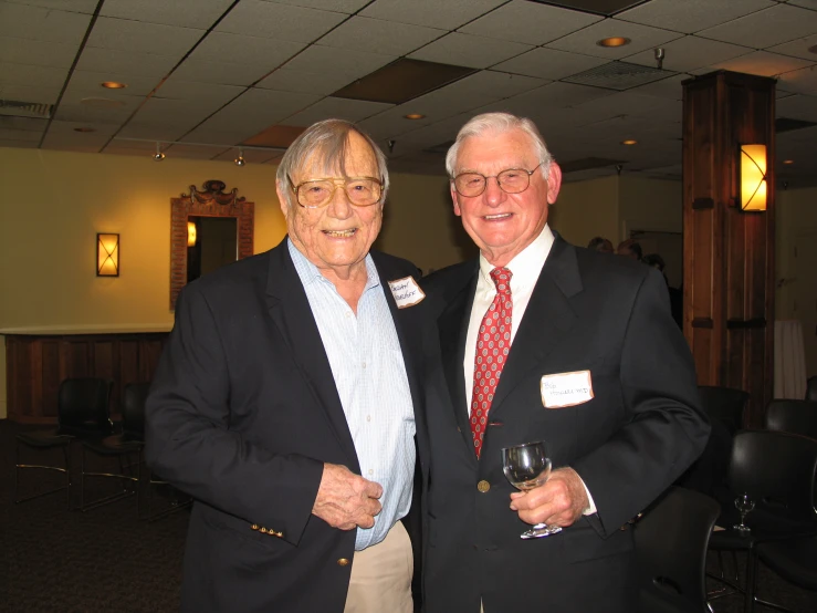 two older men dressed in business attire pose for a po