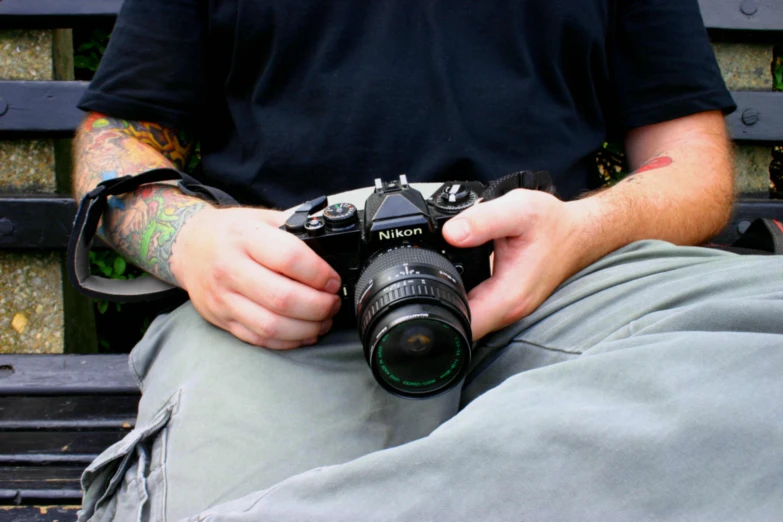 a man sitting on a bench while holding a camera