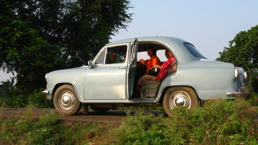 an old car with two ladies in the passenger seat