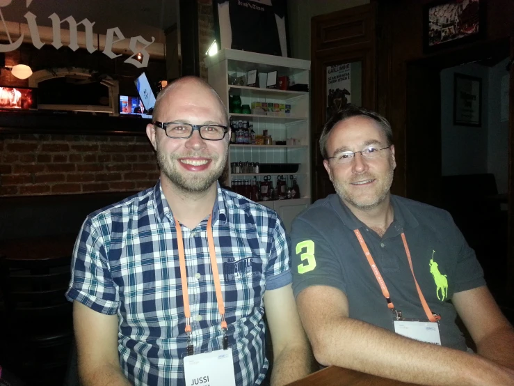 two men smile while sitting at a table