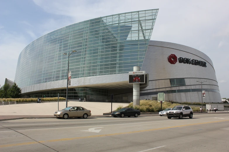 cars are driving outside of a large, modern building