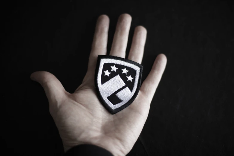 a small hand holding up a badge on it