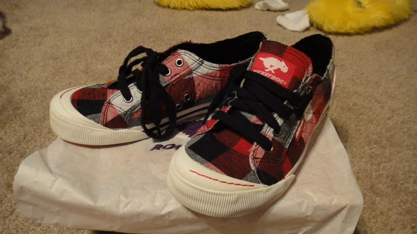 red and black sneakers sitting on top of a white plastic bag