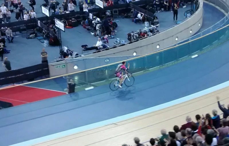 a cyclist riding through an indoor arena with a crowd