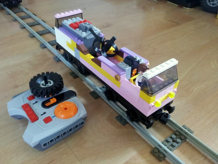 a toy train with a car sits on the tracks