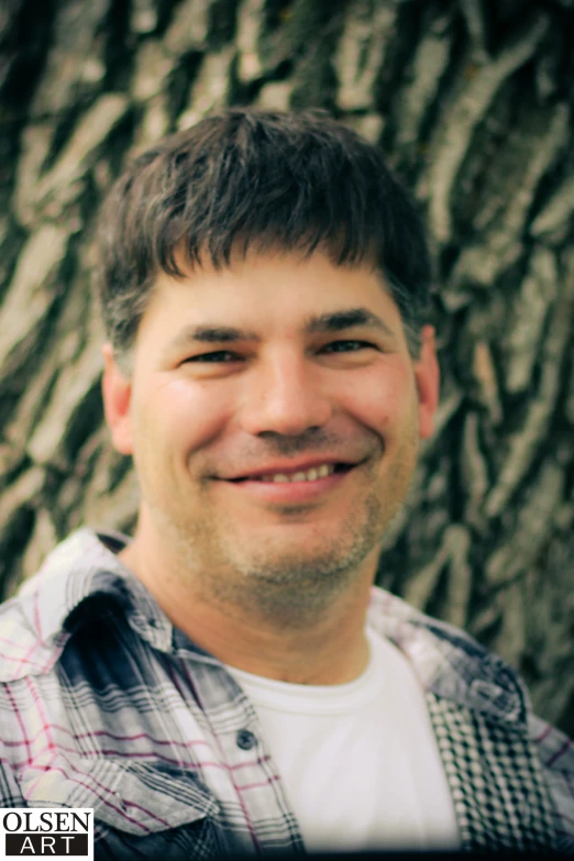 a close up of a person smiling in front of a tree