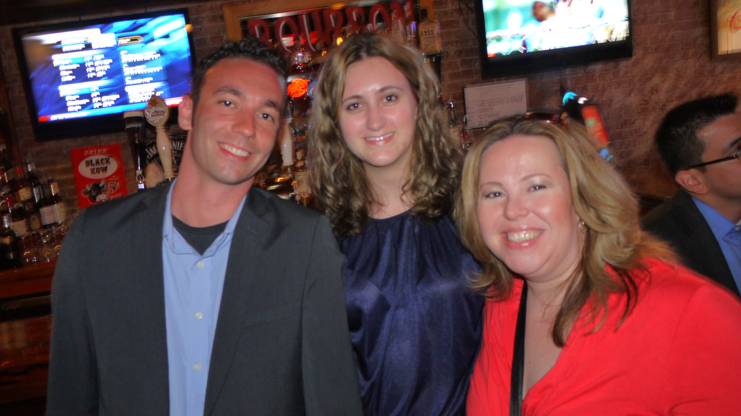 a man and two women smiling for the camera in a bar