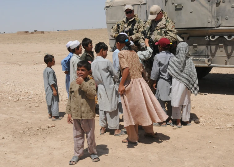 a group of people standing around a military vehicle