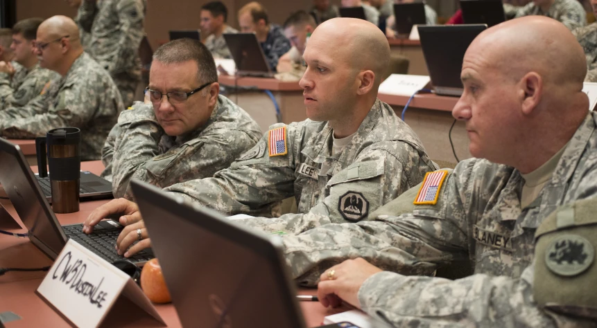 military personnel at laptops on desks and in audience