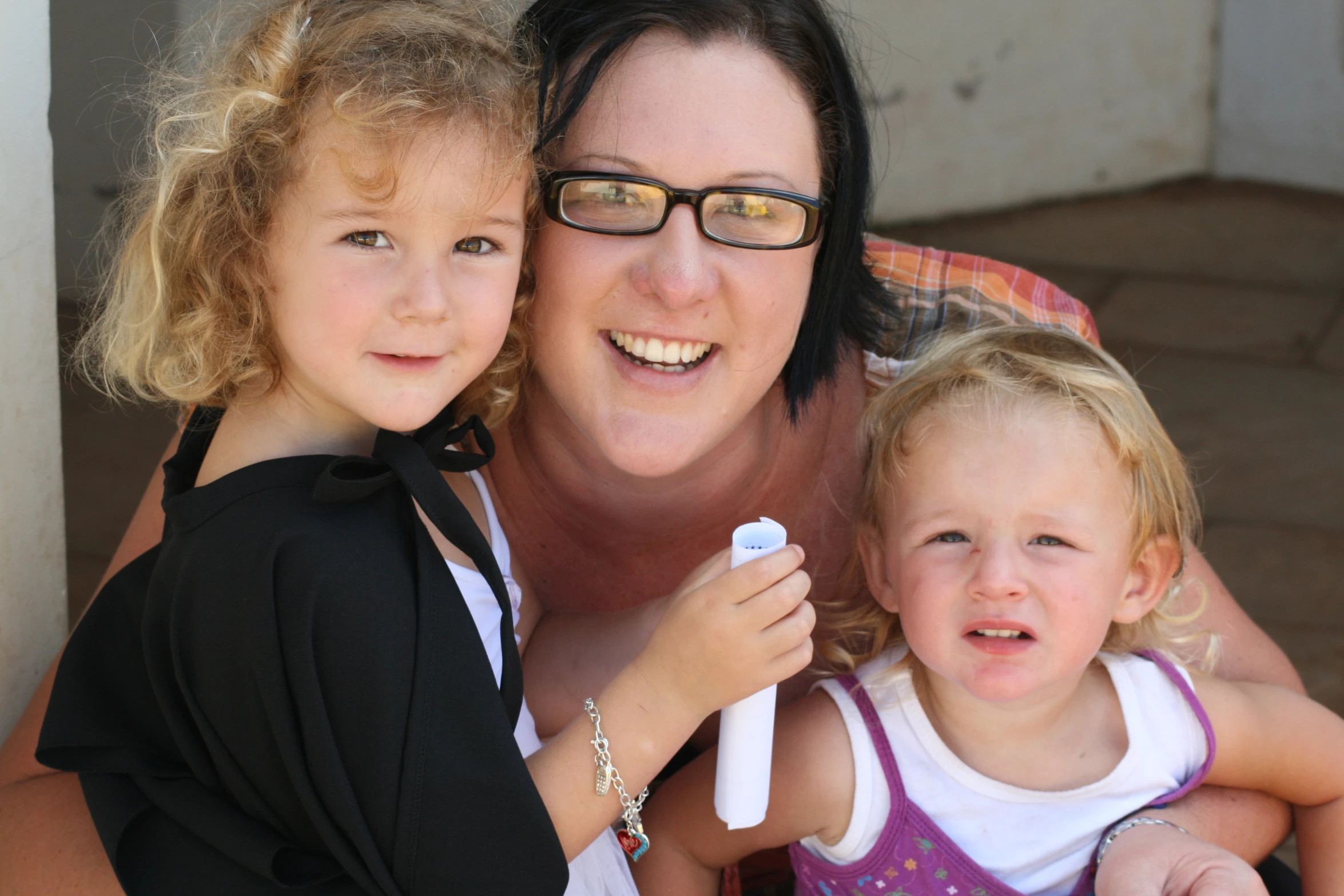 a woman is holding two small children, while smiling