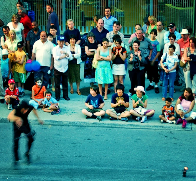 a group of people watching a boy riding a skateboard
