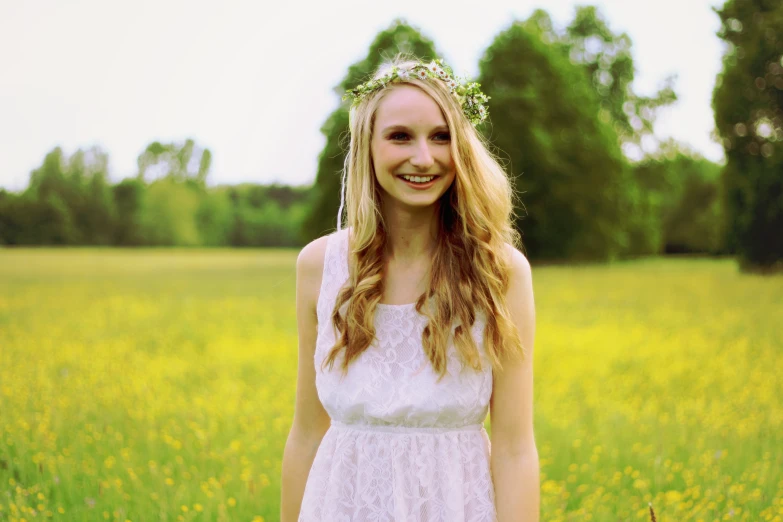 a girl standing in the grass with a flower crown