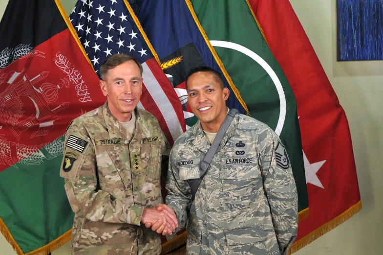 two people shaking hands in front of flags