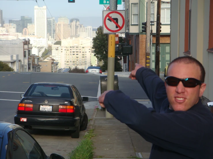 a man standing on the sidewalk next to a pole and traffic sign