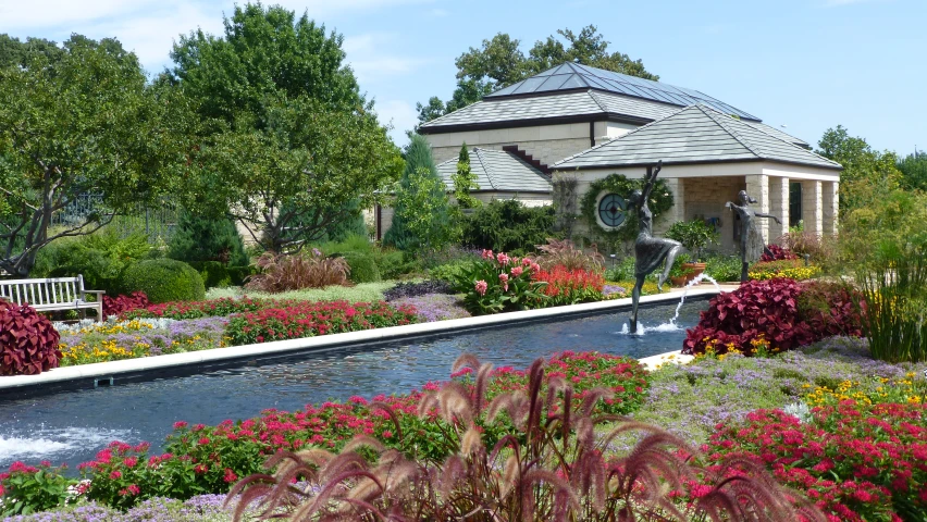 a garden with water feature and fountain with people sitting on benches