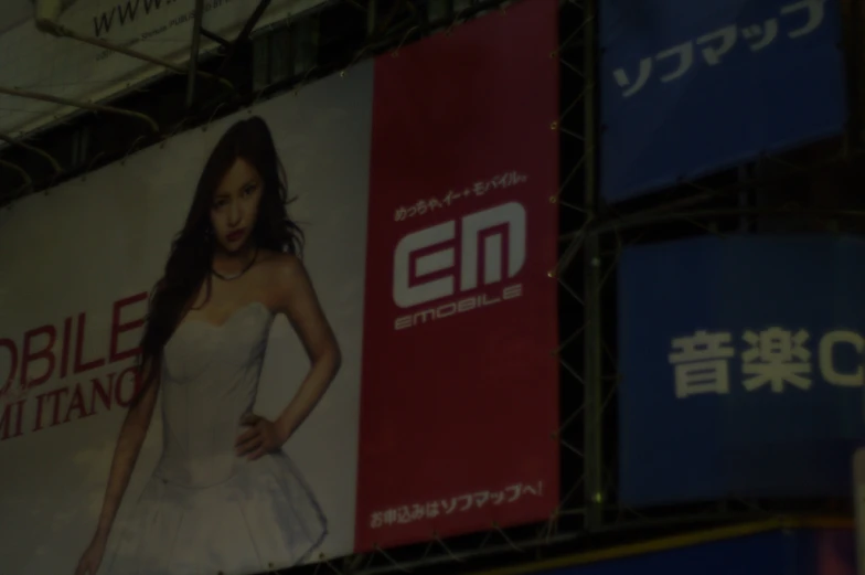 a woman in a white dress posing next to a banner on a building