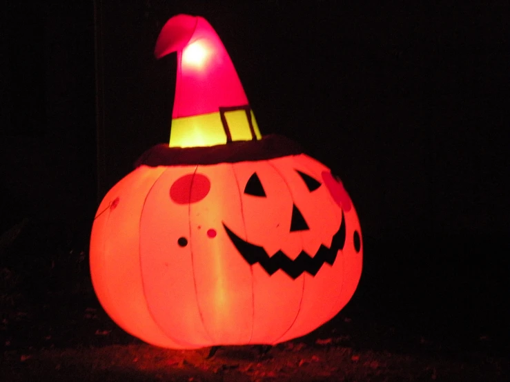 an illuminated pumpkin with a bright pink cone on it