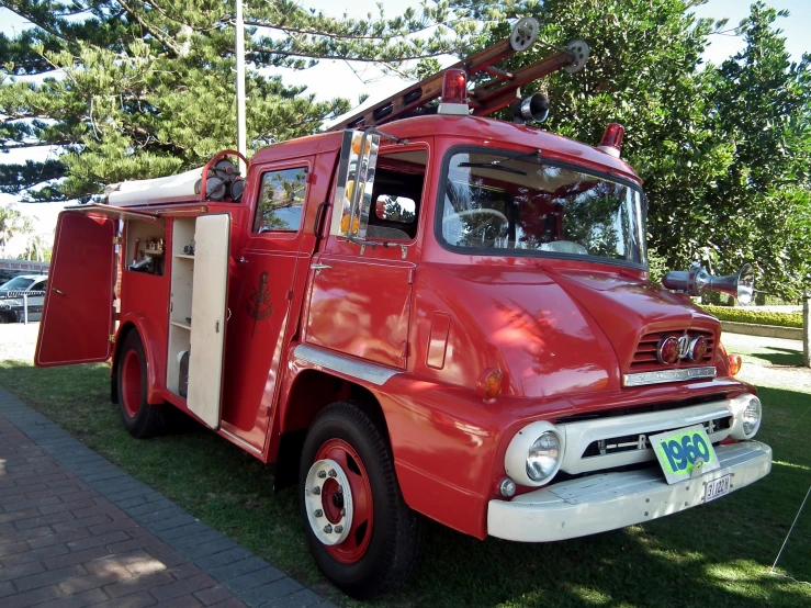 a small red fire truck parked on top of a grass covered field