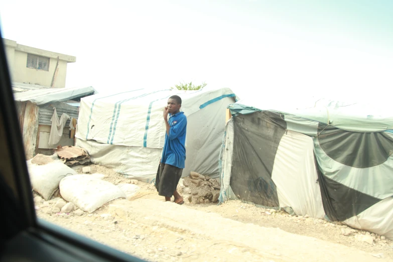 a man standing in front of tents on dirt road