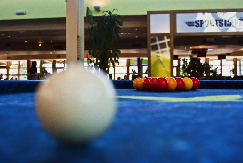 several pool balls are on the blue floor in front of an indoor bowling match area