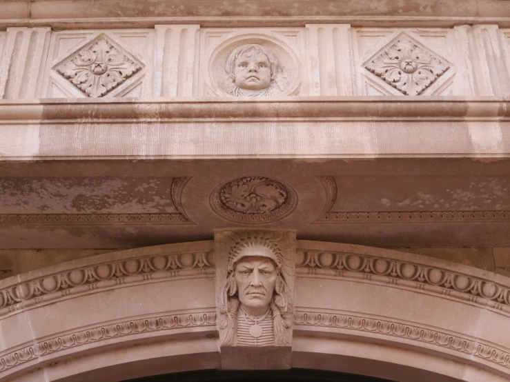 closeup of a face carving on the top of an ornate building