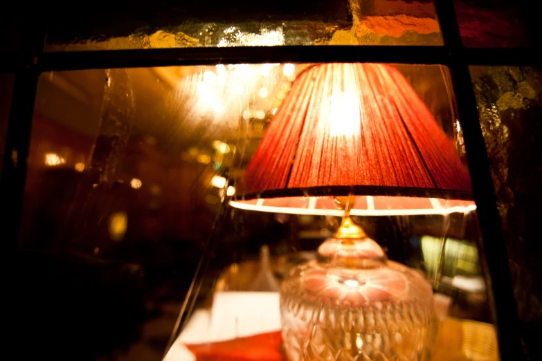 a red lamp sitting on top of a table next to a lamp