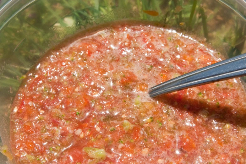 a bowl filled with meat and a spoon sitting next to some vegetables