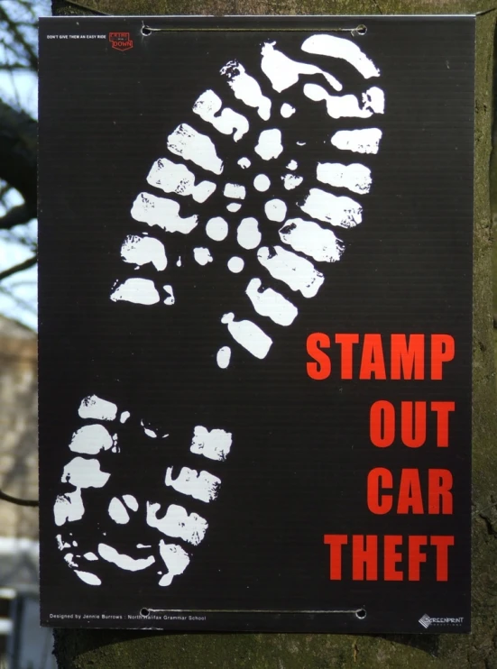 a black and red sign near a tree with white spots