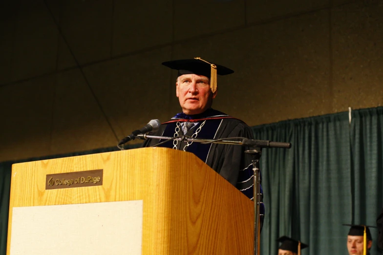 a man in a hat and gown stands in front of a podium