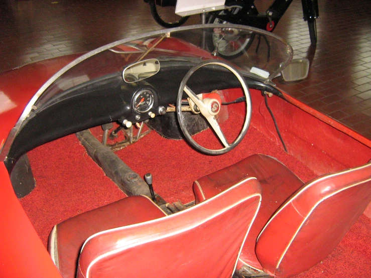 a vintage automobile with red seats is sitting in the middle of a room
