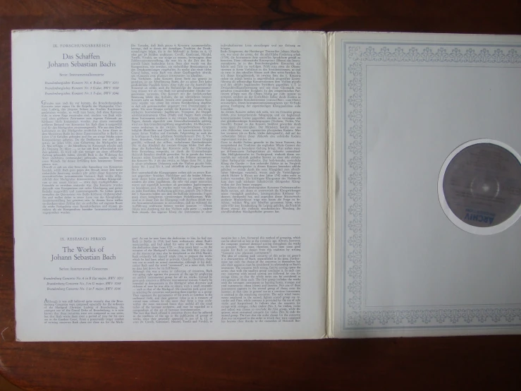 an opened book with text, an image of an object and an empty disc