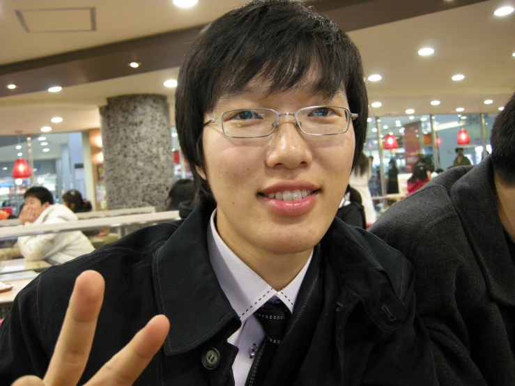 an asian guy showing the sign victory with his hand