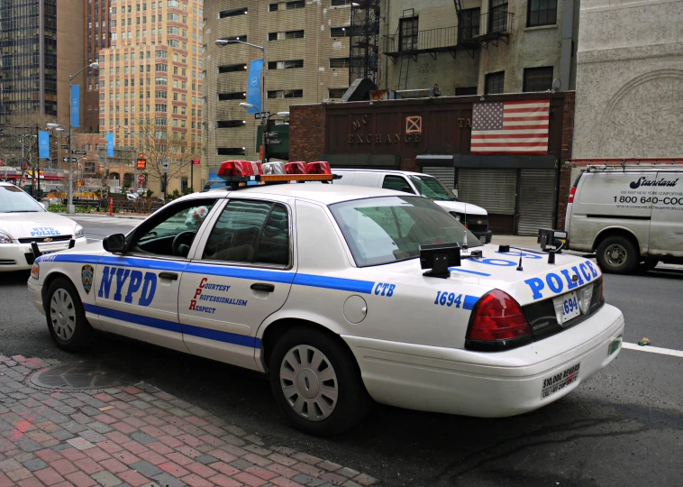 police car parked on street in city next to tall buildings