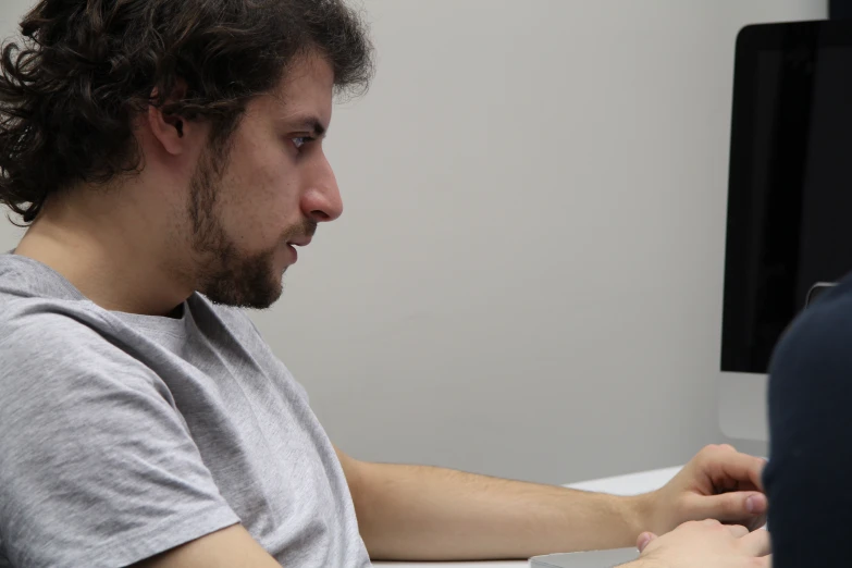 man with curly hair wearing a grey shirt