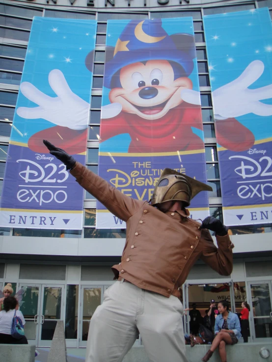 a man is performing in front of an image of mickey mouse