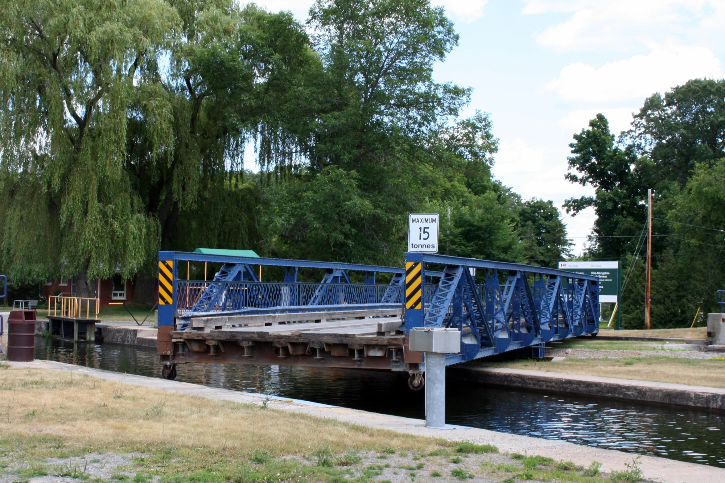 a blue rail bridge crossing a creek near trees