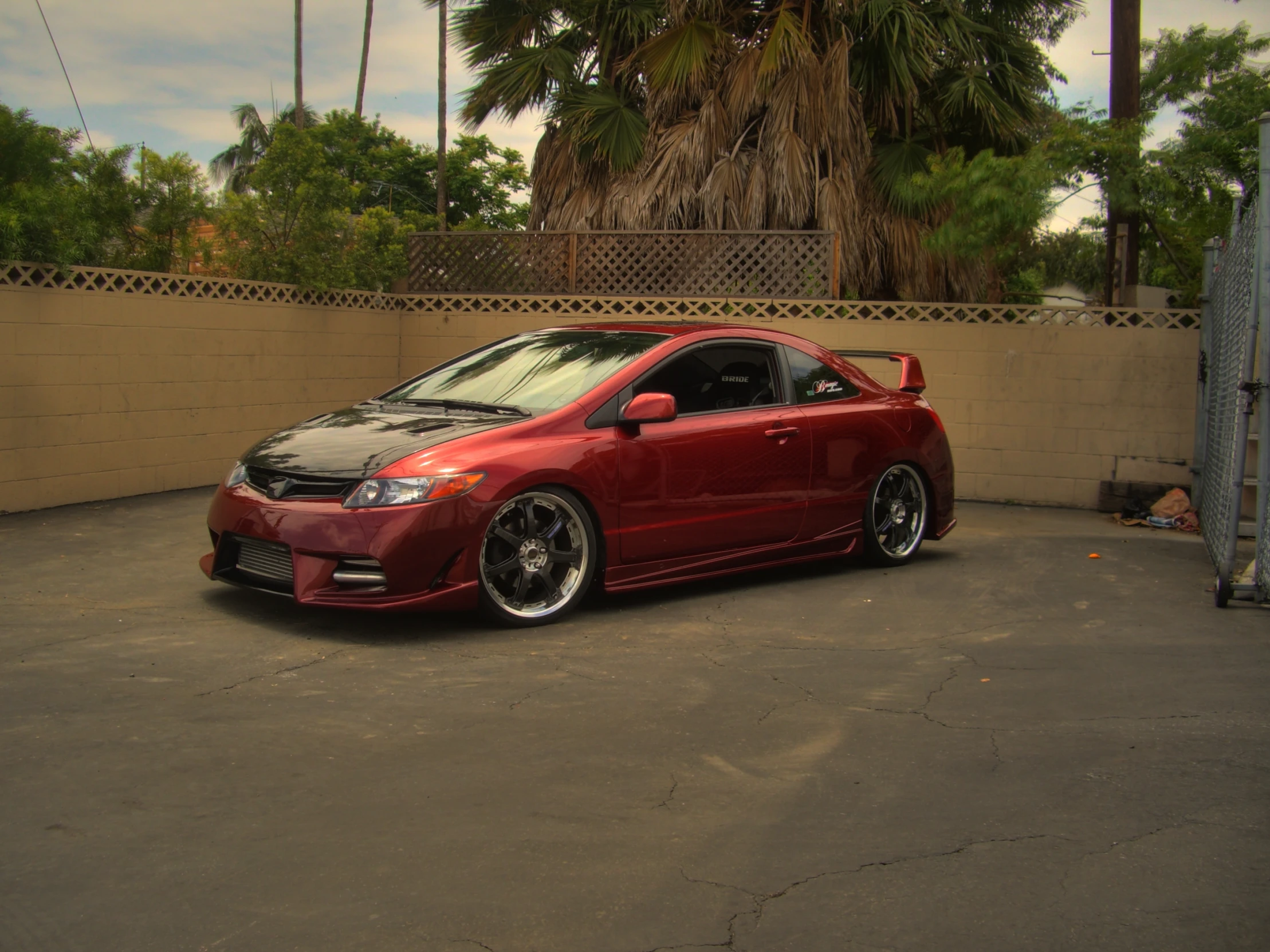 this red honda civic has black stripe and is parked near a fence