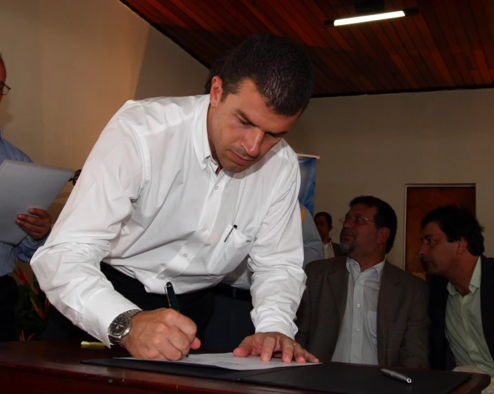 a man signing papers as men look on