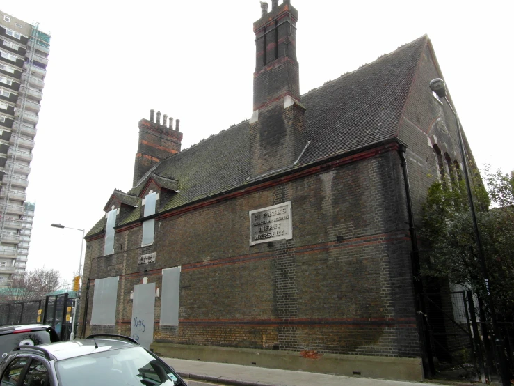 a black car parked in front of a old building with three chimneys